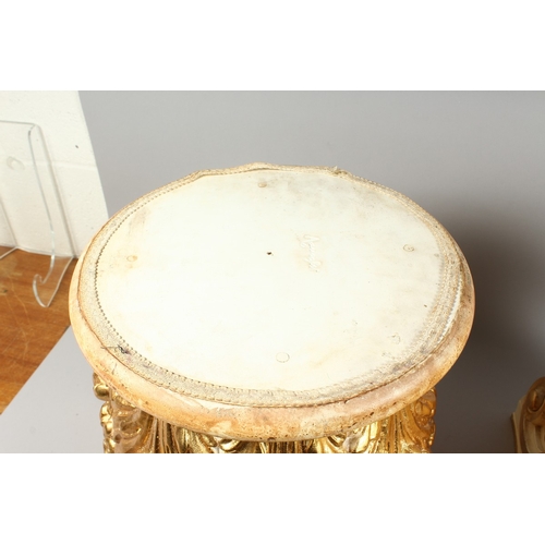 70 - A GOOD PAIR OF CREAM AND GILDED STANDS with circular tops and scrolling acanthus, 1 ft. 4 in. high.