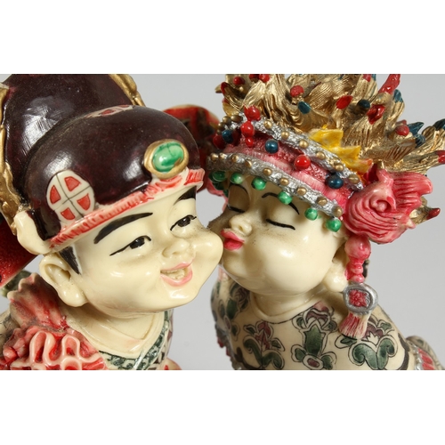 8 - A JAPANESE STYLE POTTERY GROUP of two young children kissing, 7 in. high