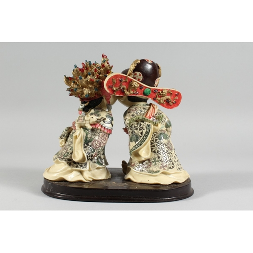 8 - A JAPANESE STYLE POTTERY GROUP of two young children kissing, 7 in. high