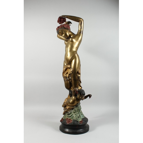 86 - A TWO COLOUR GILDED BRONZE OF A STANDING NUDE  with a cherub on a circular base, 3 ft. 3 in. high.