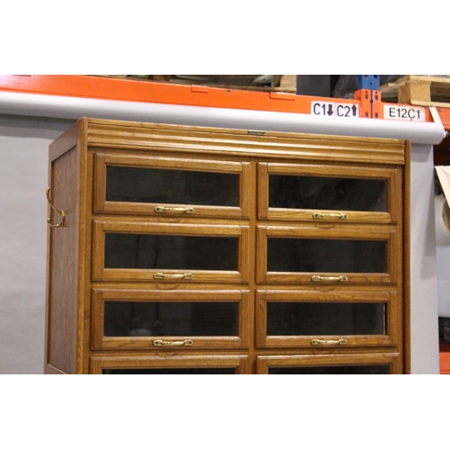 93 - A GOOD HABERDASHERY CABINET  with eight pairs of sliding glass drawers with brass handles.  The base... 