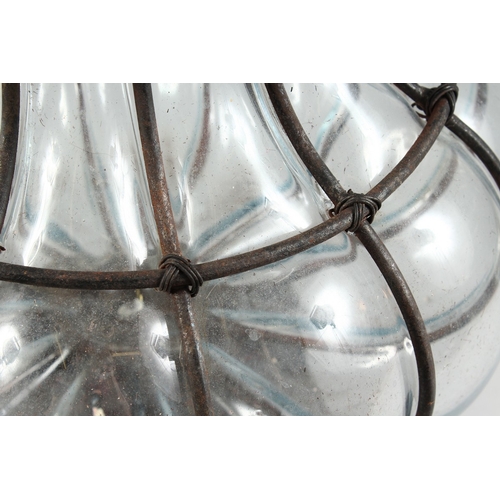 116 - A LARGE SHAPED MOULDED GLASS BULBOUS VASE in a metal stand with square base, 20 ins high.