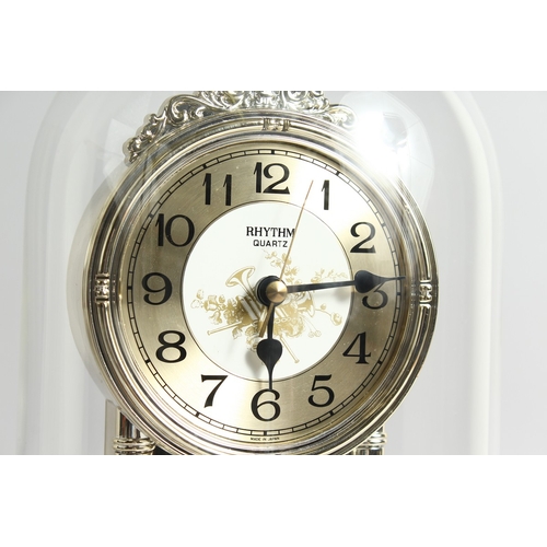 118 - A QUARTZ CLOCK in a domed cover, 11 ins high.