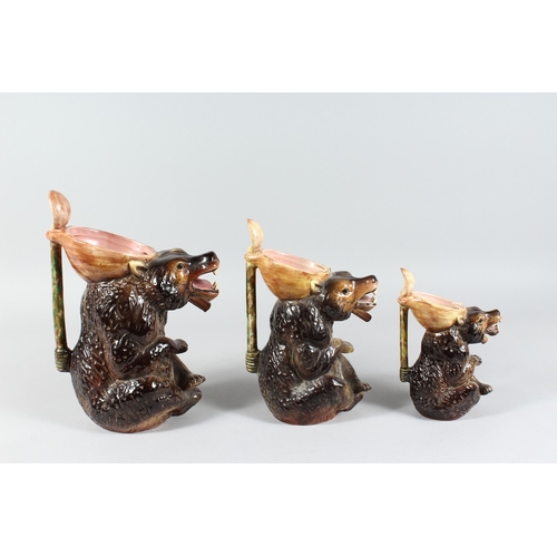 146 - A GARNITURE OF THREE PORCELAIN BEAR JUGS 13 ins, 11 ins, 8 ins high.