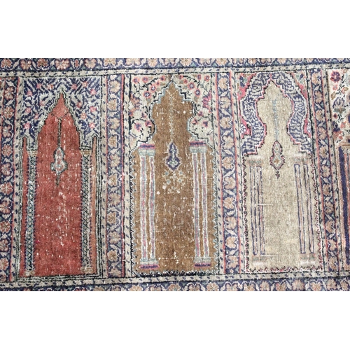 221 - AN UNUSUAL PERSIAN PRAYER RUG, the central panel with eight arches and hanging lamps, within a geome... 