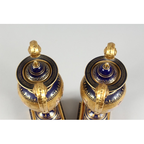 294 - A SUPERB PAIR OF VIENNA TWO HANDLED VASES AND COVERS, rich blue and gilt grounds, painted with a ban... 