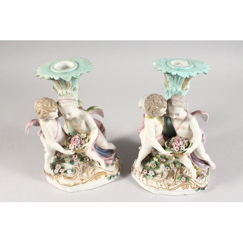 322 - A PAIR OF 19TH CENTURY MEISSEN STYLE PORCELAIN CANDLESTICK GROUP of cupids holding baskets Cross swo... 