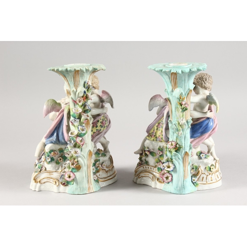 322 - A PAIR OF 19TH CENTURY MEISSEN STYLE PORCELAIN CANDLESTICK GROUP of cupids holding baskets Cross swo... 