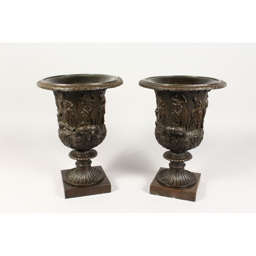 361 - A GOOD PAIR OF CLASSICAL TWO HANDLED BRONZE URNS  on square bases 12 ins high.