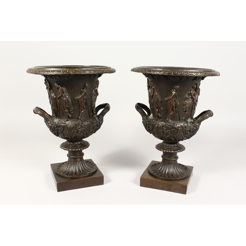 361 - A GOOD PAIR OF CLASSICAL TWO HANDLED BRONZE URNS  on square bases 12 ins high.