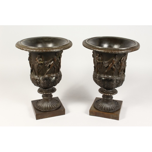 361 - A GOOD PAIR OF CLASSICAL TWO HANDLED BRONZE URNS  on square bases 12 ins high.