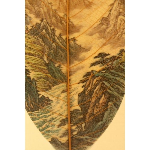 79 - A CHINESE PAINTED & FRAMED BANYAN LEAF, the leaf painted with scenes of a mountainous landscape, the... 