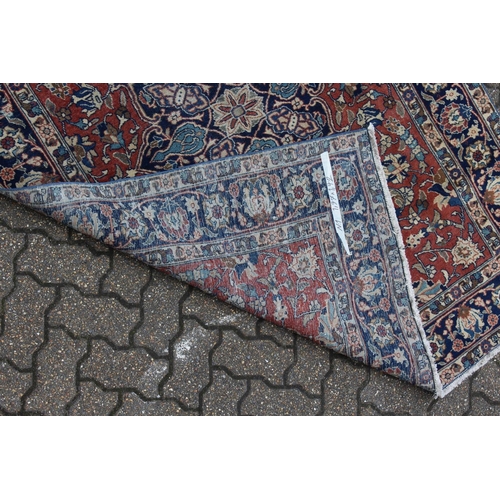 1019 - AN EARLY 20TH CENTURY PERSIAN RUG, claret ground with stylised decoration, within a blue ground bord... 