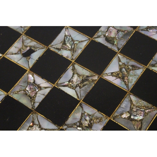 1053 - A VICTORIAN BLACK AND GILT PAPIER MACHE TILT TOP GAMES TABLE, with inlaid chess board in mother of p... 
