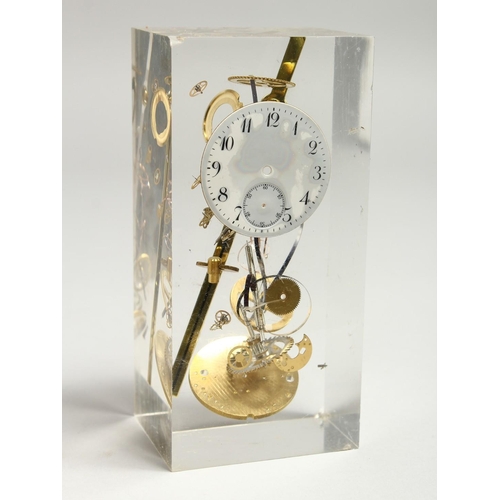 A CLOCK SCULPTURAL PIECE of watch movements, in a Perspex case. 5.25ins ...