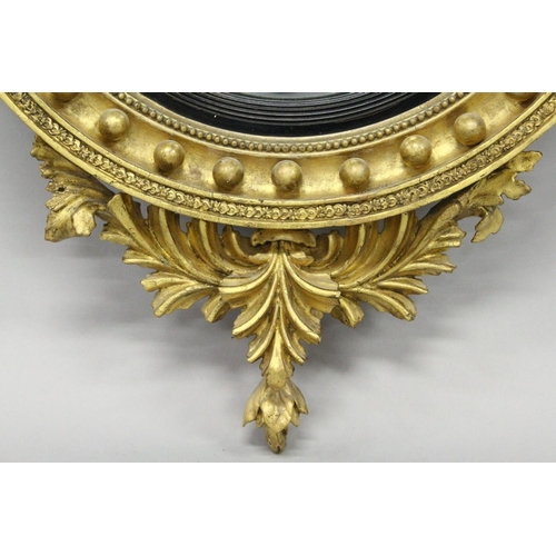 1028 - A REGENCY GILT WOOD CONVEX MIRROR with eagle cresting, ball applied frame and curved decoration to t... 