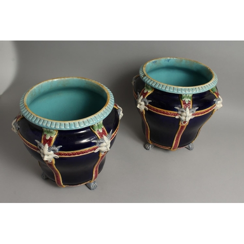 1121 - A GOOD PAIR OF MINTON BLUE AND WHITE POTTERY JARDINIERES with mask mounts on claq feet. 12ins high, ... 