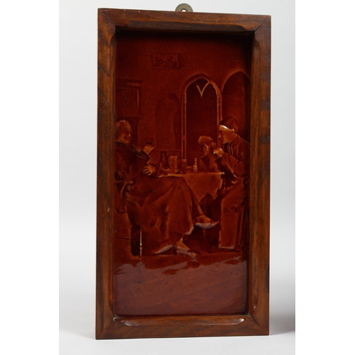 1128 - A VICTORIAN TREACLE GLAZED TILE PANEL depicting figures at a table, in an oak frame, together with a... 