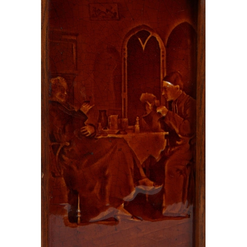 1128 - A VICTORIAN TREACLE GLAZED TILE PANEL depicting figures at a table, in an oak frame, together with a... 