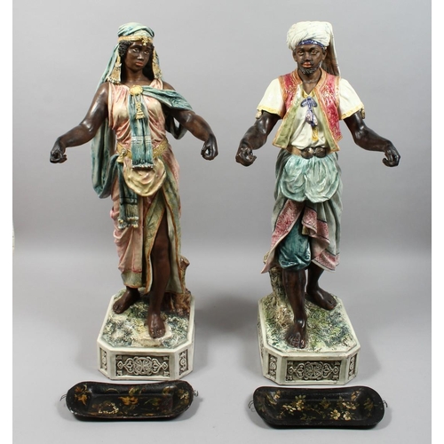 1215 - A VERY GOOD PAIR OF LARGE MAJOLICA POTTERY FIGURES OF AN ARAB MAN AND YOUNG GIRL standing holding to... 