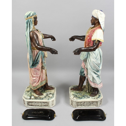 1215 - A VERY GOOD PAIR OF LARGE MAJOLICA POTTERY FIGURES OF AN ARAB MAN AND YOUNG GIRL standing holding to... 