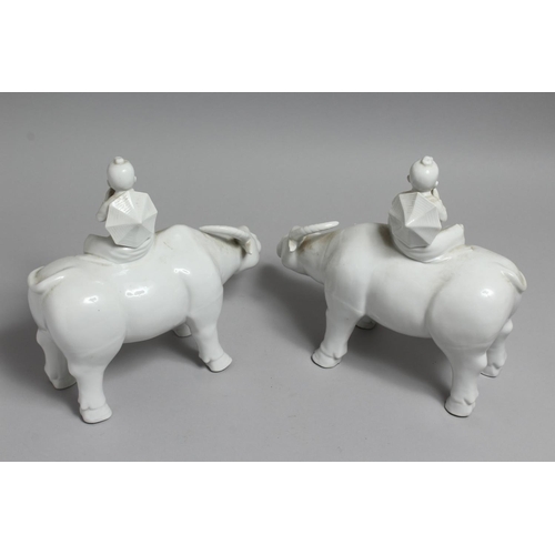 1235 - A PAIR OF CHINESE BLANC DE CHINE FIGURES OF BOYS SEATED ON WATER BUFFALO. 11ins long.