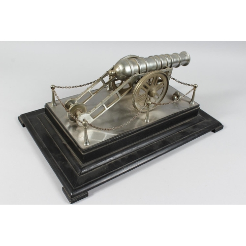 1329 - A GOOD CAST METAL MODEL OF A CANNON, on its wheeled carriage, on an ebonised plinth base. 1ft 6ins l... 