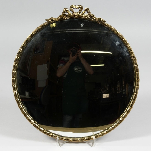 1333 - A SMALL MODERN BRASS FRAMED CONVEX MIRROR ribbon and bow cresting. 12.5ins diameter.