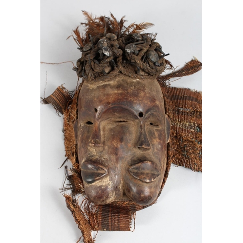 1341 - AN AFRICAN CARVED WOOD MASK  the head with nails and feathers. 13ins long.