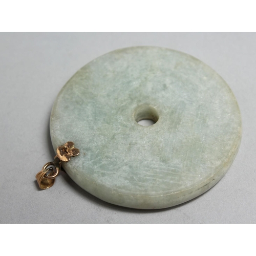 1705 - A CHINESE CIRCULAR JADE PENDANT with gold mounts, 2.25ins diameter.