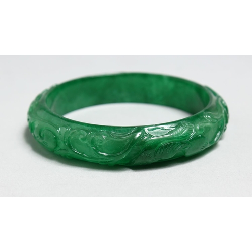 1708 - A CHINESE CARVED APPLE GREEN JADE BANGLE.