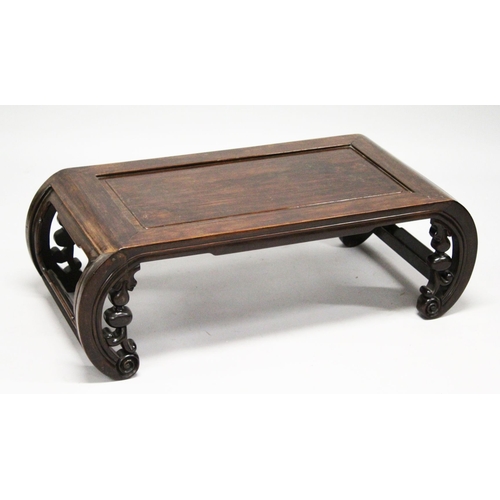 693 - A CHINESE ROSEWOOD LOW TABLE WITH PANELLED TOP, supported on curving ends with pierced and carved br... 