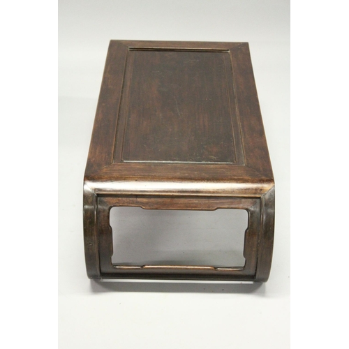 693 - A CHINESE ROSEWOOD LOW TABLE WITH PANELLED TOP, supported on curving ends with pierced and carved br... 