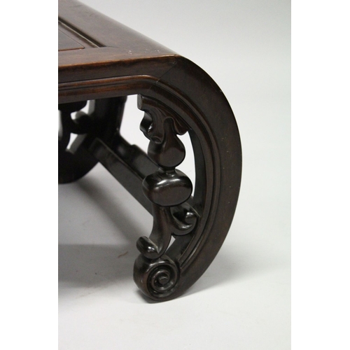 693 - A CHINESE ROSEWOOD LOW TABLE WITH PANELLED TOP, supported on curving ends with pierced and carved br... 