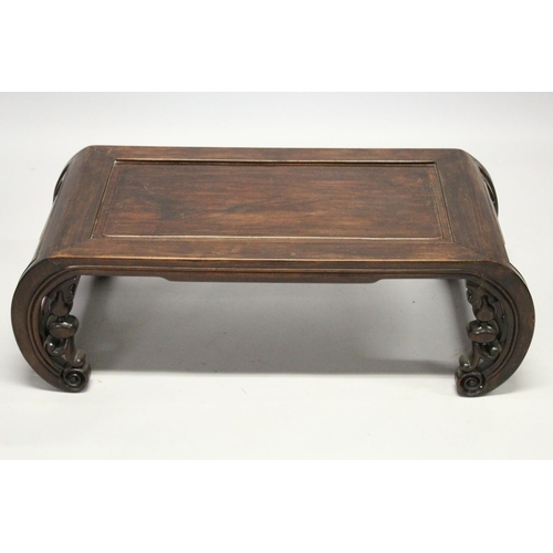 693 - A CHINESE ROSEWOOD LOW TABLE WITH PANELLED TOP, supported on curving ends with pierced and carved br... 