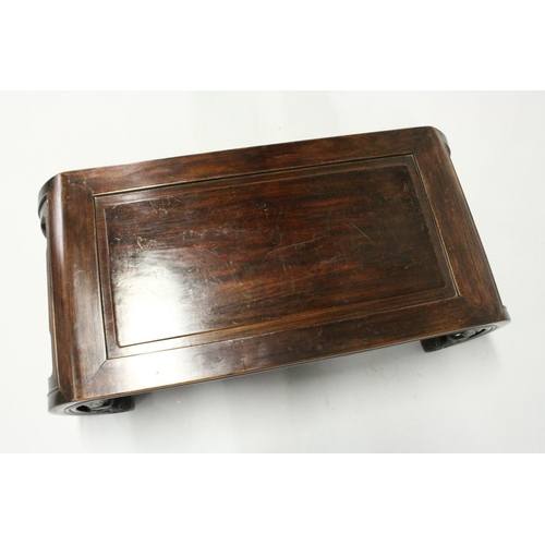 693 - A CHINESE ROSEWOOD LOW TABLE WITH PANELLED TOP, supported on curving ends with pierced and carved br... 