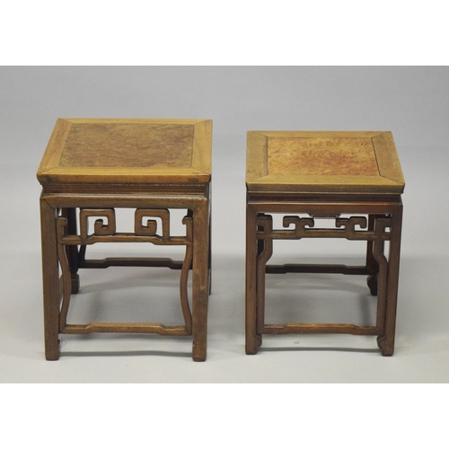 694 - TWO GOOD CHINESE HARDWOOD SQUARE STANDS, each inset with a burr wood panel, above a carved frieze su... 