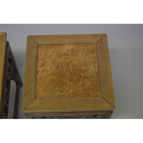 694 - TWO GOOD CHINESE HARDWOOD SQUARE STANDS, each inset with a burr wood panel, above a carved frieze su... 