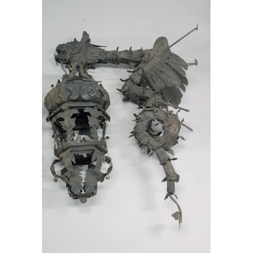 1044 - AN UNUSUAL PAIR OF WROUGHT IRON SCULPTURE LANTERNS with dragon supports. Overall height 4ft.