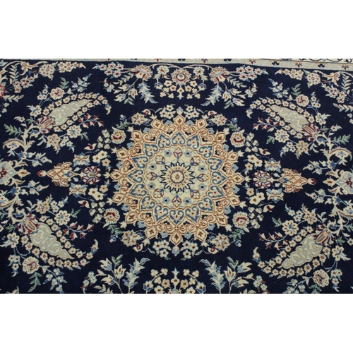 1067 - A PERSIAN RUG blue ground with central loral medallion within a cream ground floral border. 6ft 9ins... 