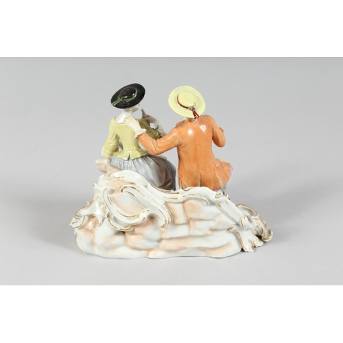 1174 - A GOOD FURSTENBERG PORCELAIN GROUP of a young man and girl siting on a bench, a basket of grapes at ... 