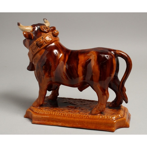 1177 - A PORTUGUESE POTTERY BULL on a rectangular base. 10ins long.