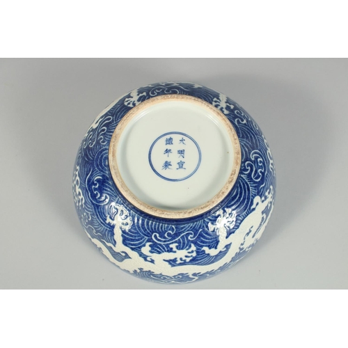 1250 - A CHINESE BLUE BOWL the sides with white dragons. 10ins diameter.