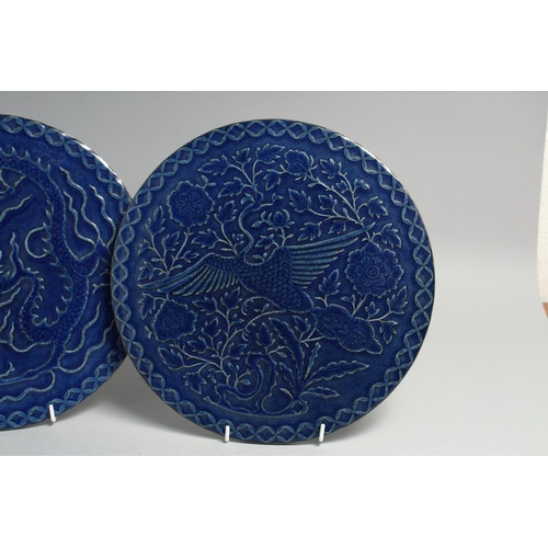 1261 - A PAIR OF CHINESE BLUE GLAZED CIRCULAR PLAQUES, one carved with a dragon, the other with an exotic b... 