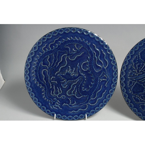 1261 - A PAIR OF CHINESE BLUE GLAZED CIRCULAR PLAQUES, one carved with a dragon, the other with an exotic b... 