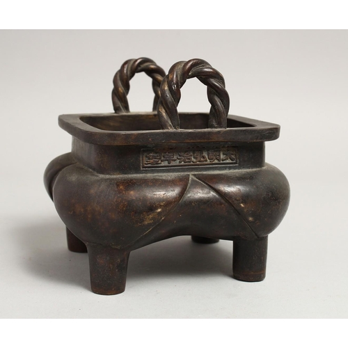 1274 - A CHINESE BRONZE SQUARE CENSER with rope handles on four curving legs, the sides with calligraphy.