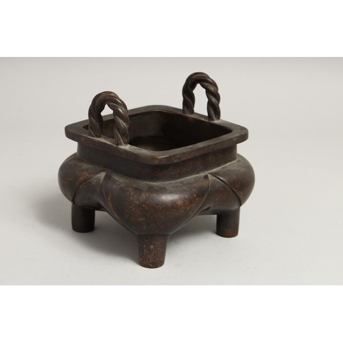 1274 - A CHINESE BRONZE SQUARE CENSER with rope handles on four curving legs, the sides with calligraphy.