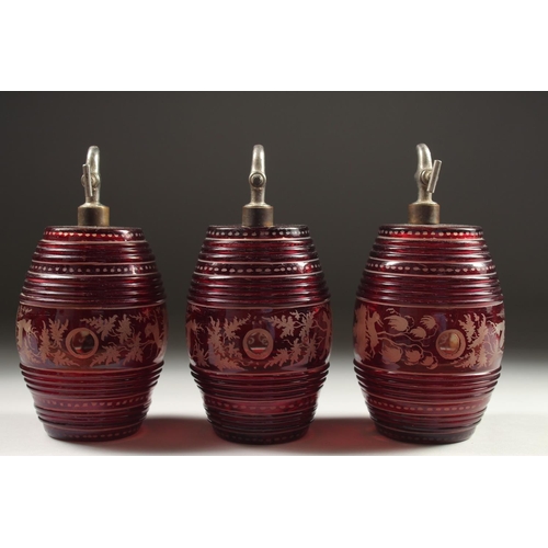 1082 - A SET OF THREE BOHEMIAN RUBY GLASS BARRELS engraved with deer and dogs, with chrome tops.