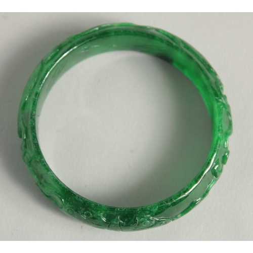 1231 - A CARVED JADE BANGLE. 2.25ins diameter.