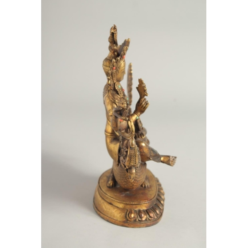 1237 - A CHINESE GILT BRONZE GOD seated on a dragon. 10ins high.